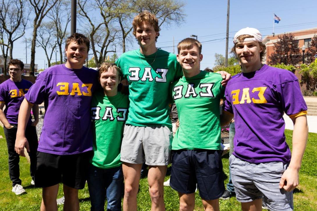 Five Kettering students wear purple or green Sigma Alpha Epsilon fraternity shirts